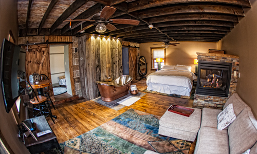 Suite with a copper soaking tub, stone fireplace and beamed barn-wood ceiling
