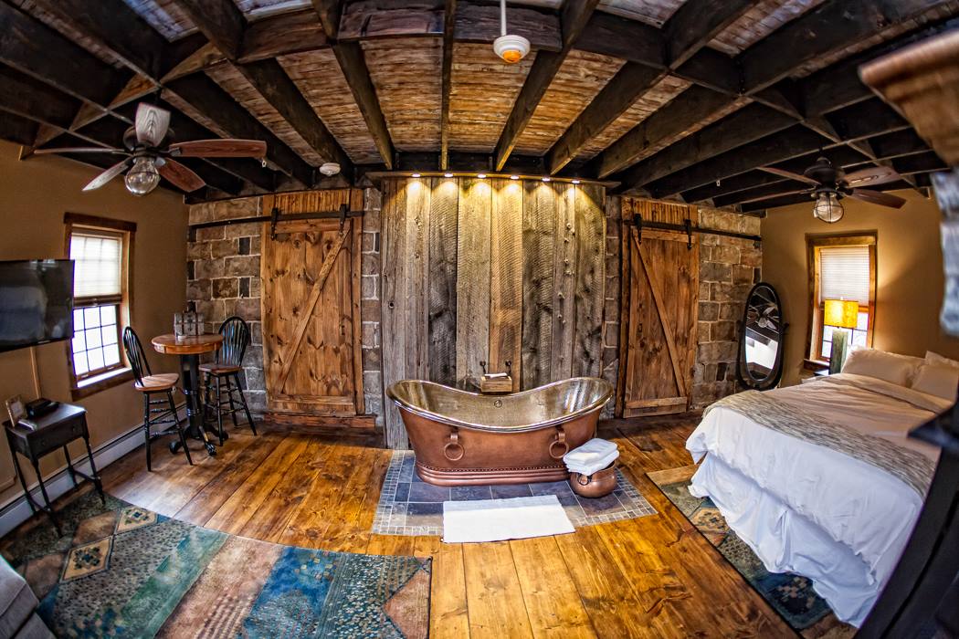 Suite with a copper soaking tub set against reclaimed barn doors