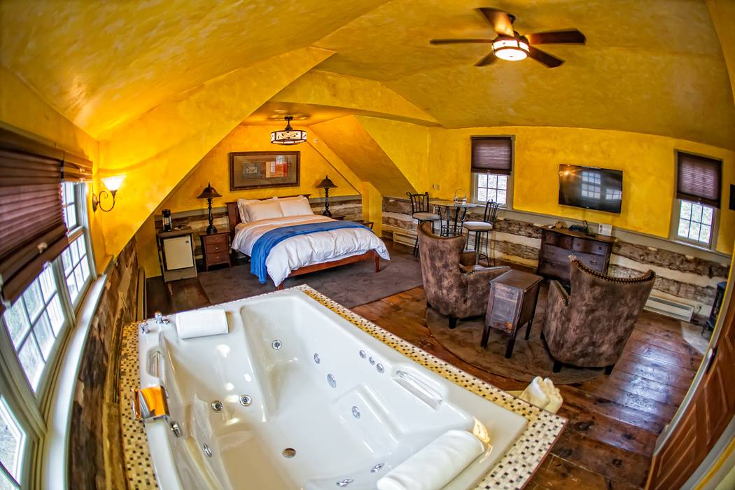 Attic suite with a large jetted tub and sitting chairs under the eaves