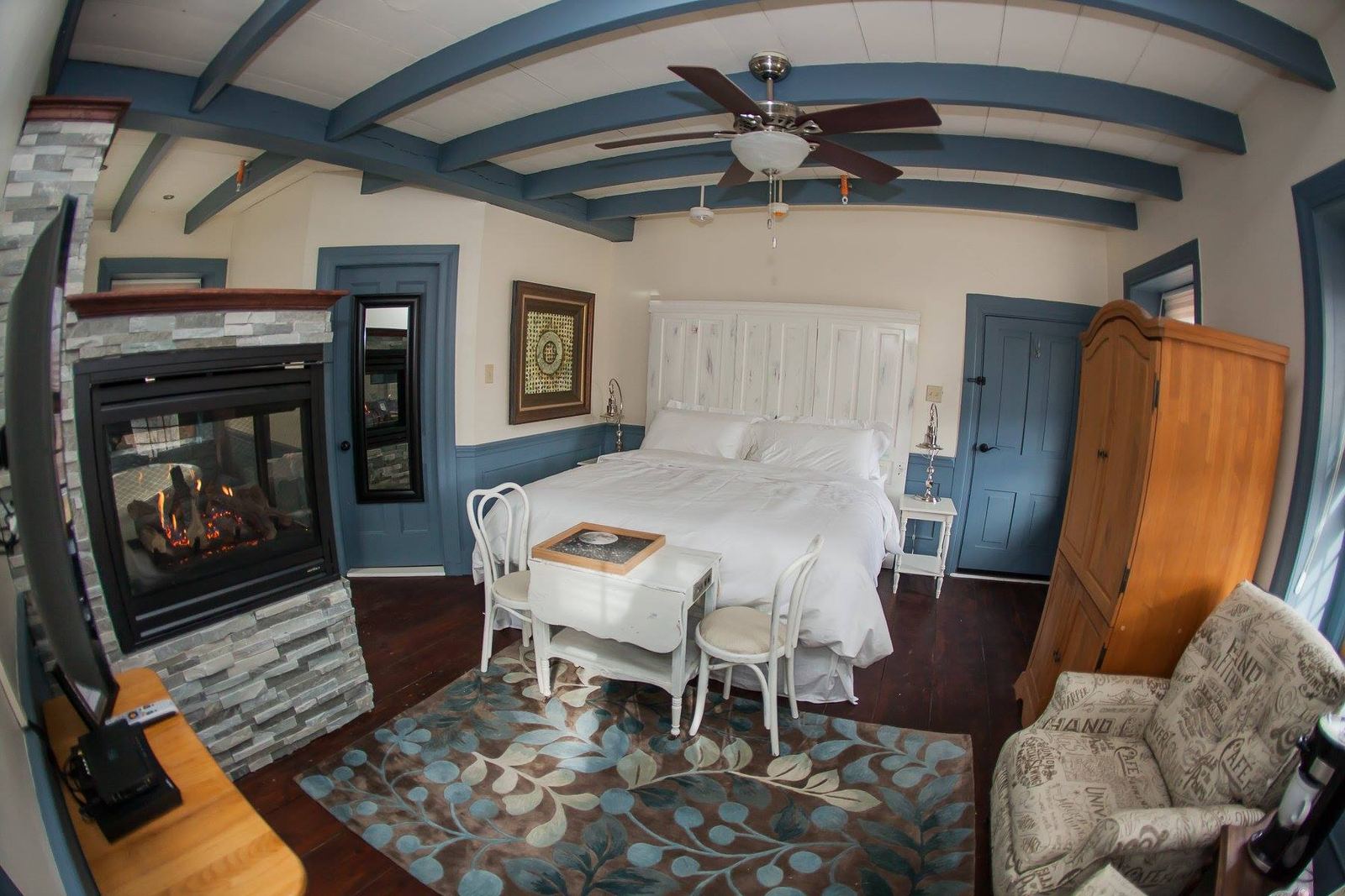 Suite in blue and white with a stone fireplace and canopy bed